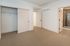 Bright empty bedroom with neutral carpeting, spacious closet, and modern en-suite bathroom.