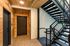 Modern apartment corridor with sleek metal staircase and inviting wood-paneled walls, leading to a secure entry door.