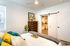 Bright and stylish bedroom with modern decor, featuring vibrant pillows, elegant artwork, and a spacious walk-in closet with a sliding barn door.