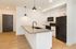 Modern kitchen with sleek black appliances, bright lighting, and a spacious island, perfect for stylish living.