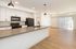 Modern open-concept kitchen with sleek black appliances, elegant pendant lighting, and spacious living area with natural light.