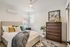 Chic bedroom with modern decor featuring a plush bed, elegant artwork, and abundant natural light.