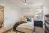 Cozy bedroom with a stylish design, featuring a plush bed, chic pillows, and ample natural light streaming through large windows.