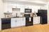 Modern kitchen with sleek white cabinets, black appliances, and elegant wood flooring, perfect for contemporary living.