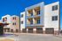 Modern multi-story apartment building with contemporary balconies and stylish facade set against a clear blue sky.