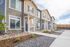 Charming townhouse complex with modern stone accents and inviting entryways, surrounded by tidy landscaping and a spacious sidewalk.