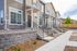Charming row of modern townhouses with elegant entrances and beautifully landscaped pathways under a clear blue sky, perfect for contemporary family living.