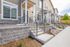 Charming townhouse exterior with inviting steps, elegant stonework, and lush landscaping, perfect for modern living.