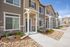Modern townhouse exterior showcasing elegant stonework, inviting porches, and neatly landscaped pathways under a clear blue sky.