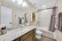 Elegant bathroom featuring a granite countertop, modern fixtures, and a cozy bathtub with stylish gray towels.