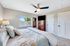 Inviting bedroom with elegant decor, featuring a ceiling fan, cozy bed, and ample natural light from a large window.