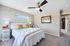 Bright and inviting bedroom with modern ceiling fan, plush bedding, and stylish decor, creating a cozy and elegant atmosphere.