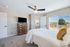 Bright and cozy bedroom with modern ceiling fan, large window with scenic view, and stylish furnishings.