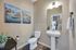 Chic bathroom with elegant fixtures, featuring stylish wall art and a sleek pedestal sink, creating a serene and welcoming atmosphere.