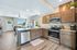 Bright and airy living space featuring a modern kitchen with stainless steel appliances, granite countertops, and open access to a stylish, sunlit living room.