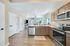Inviting open-concept kitchen and living area with modern appliances, granite countertops, and elegant hardwood floors, illuminated by natural light.