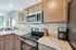 Contemporary kitchen with sleek wooden cabinets, modern stainless steel appliances, and elegant granite countertops overlooking a bright living area.
