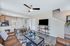 Modern living area with cozy brown leather sofa, sleek open kitchen with bar stools, and elegant glass coffee table showcasing vibrant decor.