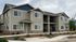 Charming two-story apartment complex with modern architecture, featuring large windows and inviting balconies surrounded by neatly landscaped greenery.
