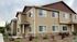 Charming two-story townhouse with elegant siding, large windows, and landscaped front yard under a serene sky.
