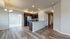Modern kitchen area featuring sleek granite countertops, stainless steel appliances, and elegant dark wood cabinets adjacent to a bright, open dining space with a stylish chandelier.