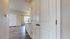 Inviting apartment entryway with sleek hardwood floors leading to a bright, open-concept area featuring a modern kitchen and large window.