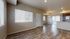 Bright and airy living area with wood flooring, large windows, and open kitchen leading to a charming balcony.