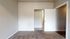 Inviting apartment room with plush carpet flooring, neutral paint, and open doorway leading to adjacent spaces.