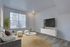 Bright and inviting living room with large window view, modern decor, and wall-mounted TV for ultimate relaxation.