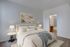 Elegant bedroom with soft lighting, featuring a plush bed, artistic floral wall decor, and a glimpse into a stylish bathroom.