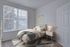 Charming bedroom with a cozy bed, large window offering bright natural light, and stylish decor exuding warmth and comfort.