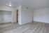 Bright and inviting living space with modern flooring and open layout, leading into a cozy kitchen area.