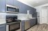 Modern kitchen with sleek gray cabinetry, stainless steel appliances, and elegant wood flooring, offering a chic and functional space.