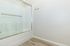 Modern bathroom with sleek glass shower door and elegant wood flooring, perfect for a relaxing experience.