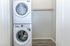 Modern laundry space featuring a sleek stacked washer and dryer in a bright, compact area with minimalist design.