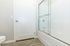 Bright and modern bathroom featuring elegant glass shower doors and chic wood-style flooring.