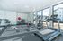 Bright and modern fitness center featuring state-of-the-art treadmill, elliptical machine, and free weights, with ample natural light from large windows.