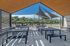 Chic outdoor patio with modern seating, elegant shade sails, and a scenic river view.