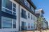 Modern apartment exterior showcasing sleek design with large windows, contemporary architecture, and vibrant landscaping under a clear blue sky.