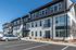 Modern apartment building exterior with sleek black and white design, large windows, and convenient parking area.