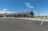 Contemporary single-story commercial building with sleek black exterior, large windows, and a spacious parking lot, set against a picturesque blue sky and mountain backdrop.