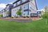 Modern apartment complex 'The Eddy' with elegant architecture, manicured landscaping, and inviting green spaces.