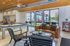 Modern, open-concept living space with a cozy leather sofa, stylish armchairs, and a sleek pool table. Large windows let in ample natural light, creating a warm and inviting atmosphere perfect for relaxation and entertaining.