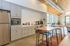 Elegant modern kitchen with sleek gray cabinetry, stainless steel appliances, and inviting dining area with large windows.