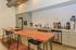 Modern kitchen space featuring natural wood tables, sleek cabinetry, and a variety of beverage options for a stylish and inviting atmosphere.