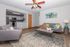 Bright open-concept living room with stylish modern decor, featuring a cozy sofa, vibrant cushions, and a sleek kitchen in the background.