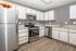 Modern kitchen with stainless steel appliances, sleek cabinetry, and elegant wood flooring.
