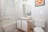 Elegant bathroom featuring a pristine bathtub, stylish vanity with mirror, and a touch of nature with floral artwork.