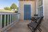 Charming apartment patio featuring cozy wicker chairs and a small round table, inviting outdoor relaxation with scenic views of lush greenery.