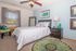 Inviting bedroom with plush carpeting, stylish decor, and natural light through a large window, creating a cozy oasis.